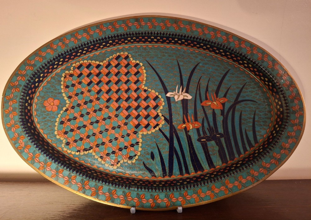 An oval Japanese cloisonne enamel tray featuring a turquoise background decorated with blue and orange iris flowers alongside geometric lattice patterns. View II