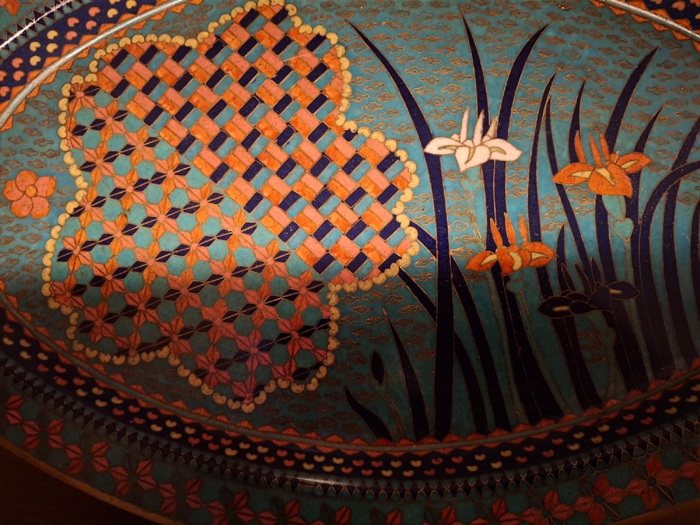 An oval Japanese cloisonne enamel tray featuring a turquoise background decorated with blue and orange iris flowers alongside geometric lattice patterns. View X