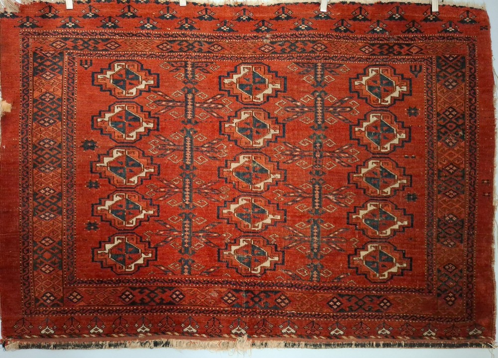 A rectangular antique handwoven wool Ersari Turkoman chuval face featuring fifteen stepped octagonal gul motifs arranged on a deep rust-red field within geometric borders.