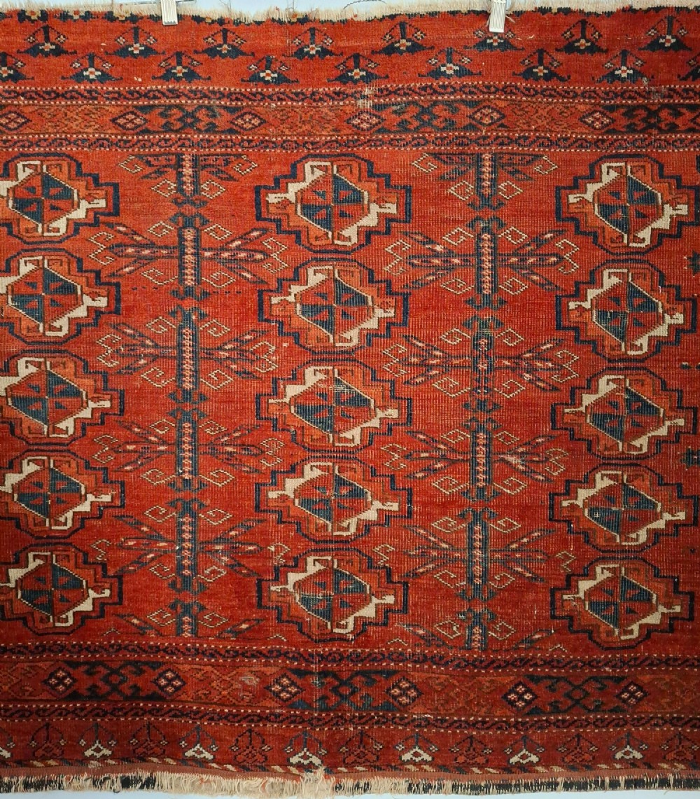 A rectangular antique handwoven wool Ersari Turkoman chuval face featuring fifteen stepped octagonal gul motifs arranged on a deep rust-red field within geometric borders. View V