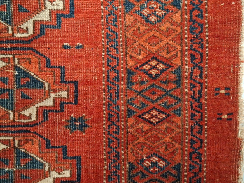 A rectangular antique handwoven wool Ersari Turkoman chuval face featuring fifteen stepped octagonal gul motifs arranged on a deep rust-red field within geometric borders. View VII