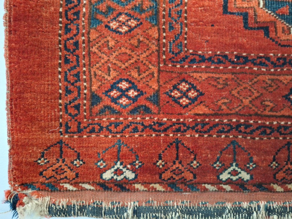 A rectangular antique handwoven wool Ersari Turkoman chuval face featuring fifteen stepped octagonal gul motifs arranged on a deep rust-red field within geometric borders. View X