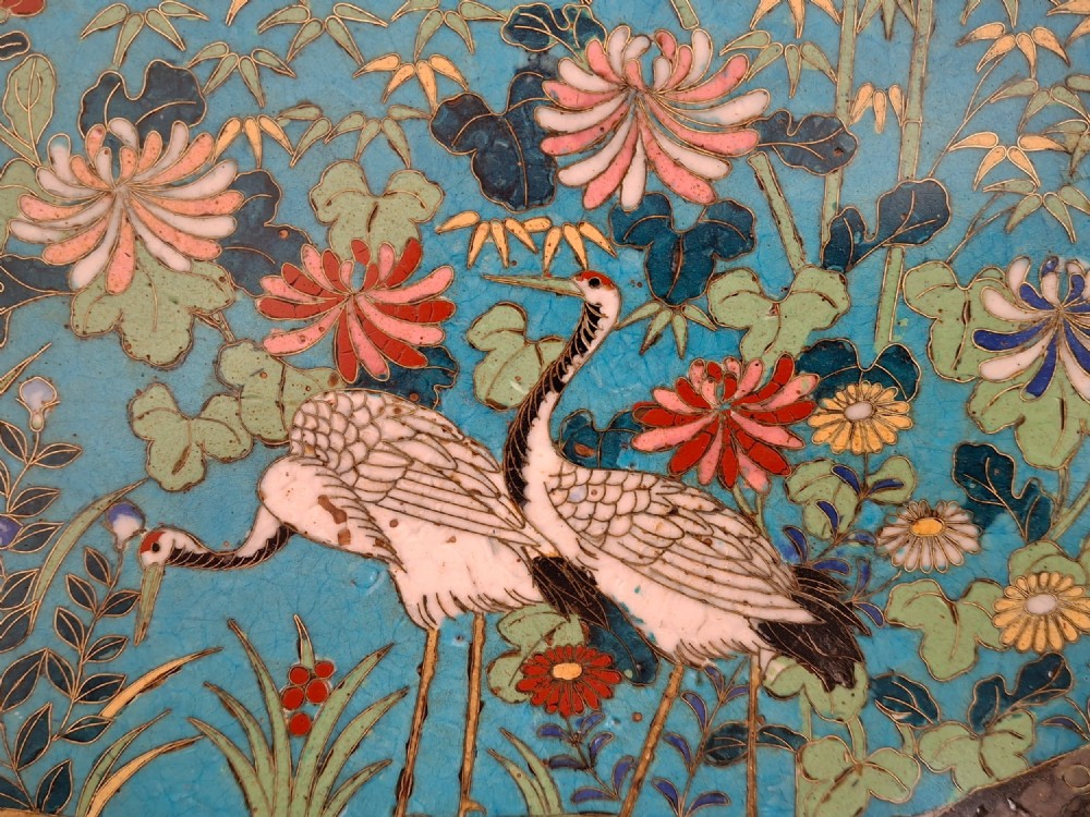 A circular Japanese cloisonne enamel decorative plate decorated with two wading birds surrounded by flowers against a turquoise ground with an ornamental geometric border. View II