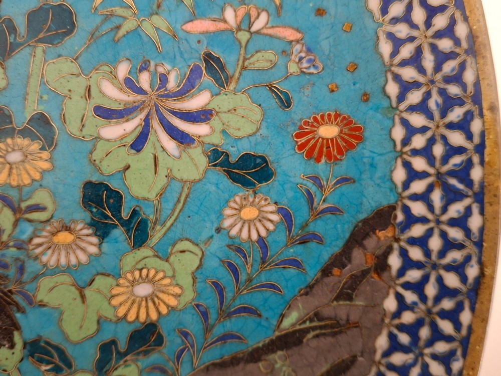 A circular Japanese cloisonne enamel decorative plate decorated with two wading birds surrounded by flowers against a turquoise ground with an ornamental geometric border. View IX