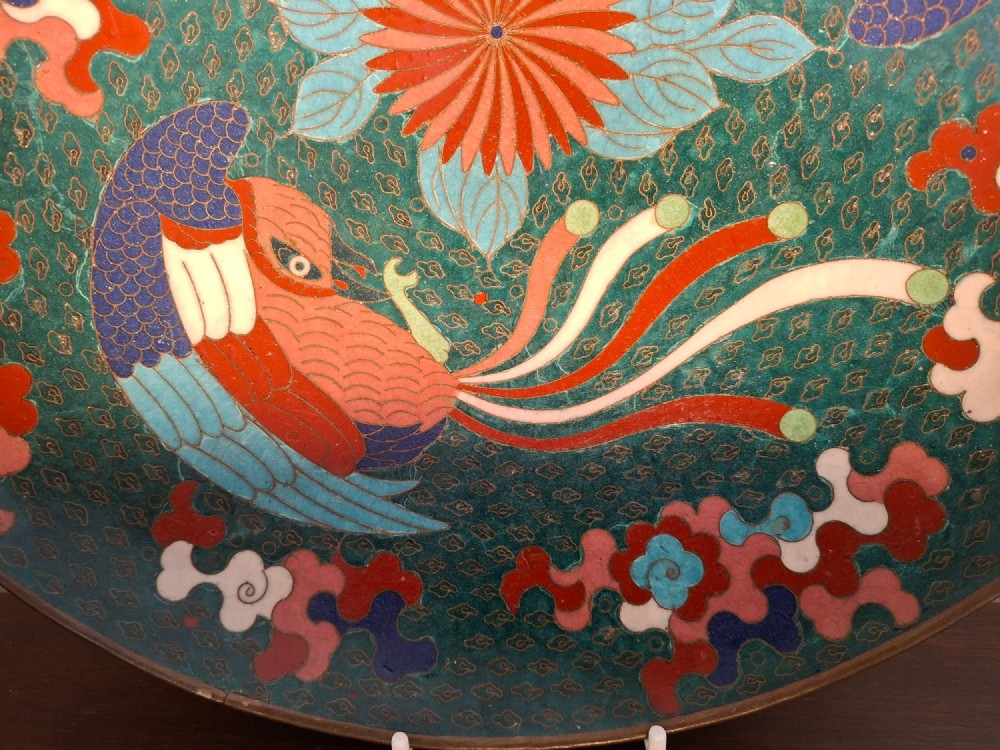 A circular antique Japanese cloisonne enamel charger decorated with two colourful Ho-o phoenix birds and a central floral chrysanthemum motif against a dark teal pattern. View III