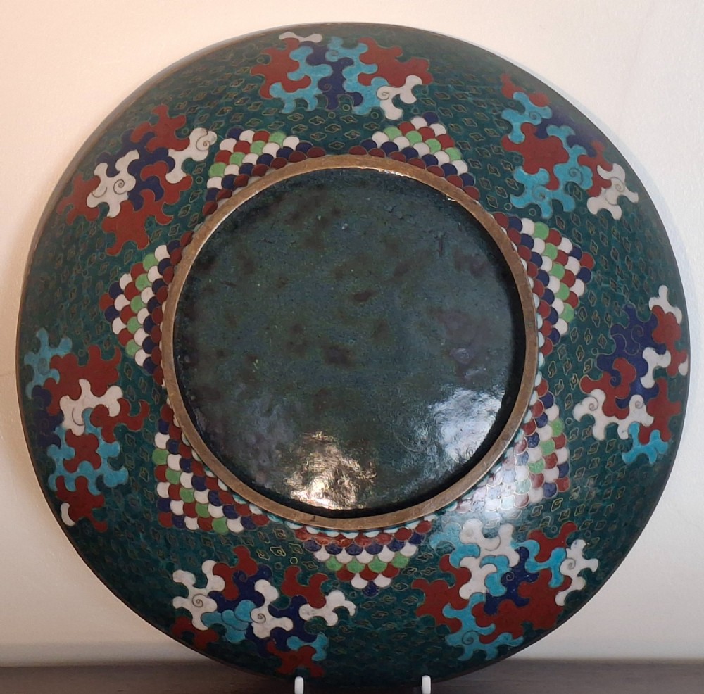 A circular antique Japanese cloisonne enamel charger decorated with two colourful Ho-o phoenix birds and a central floral chrysanthemum motif against a dark teal pattern. View XII