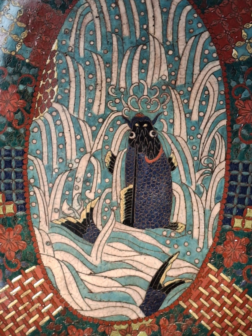 An oval Japanese cloisonne enamel tray displaying a central blue leaping koi carp within stylized waves, surrounded by geometric and red floral patterned borders. View XI