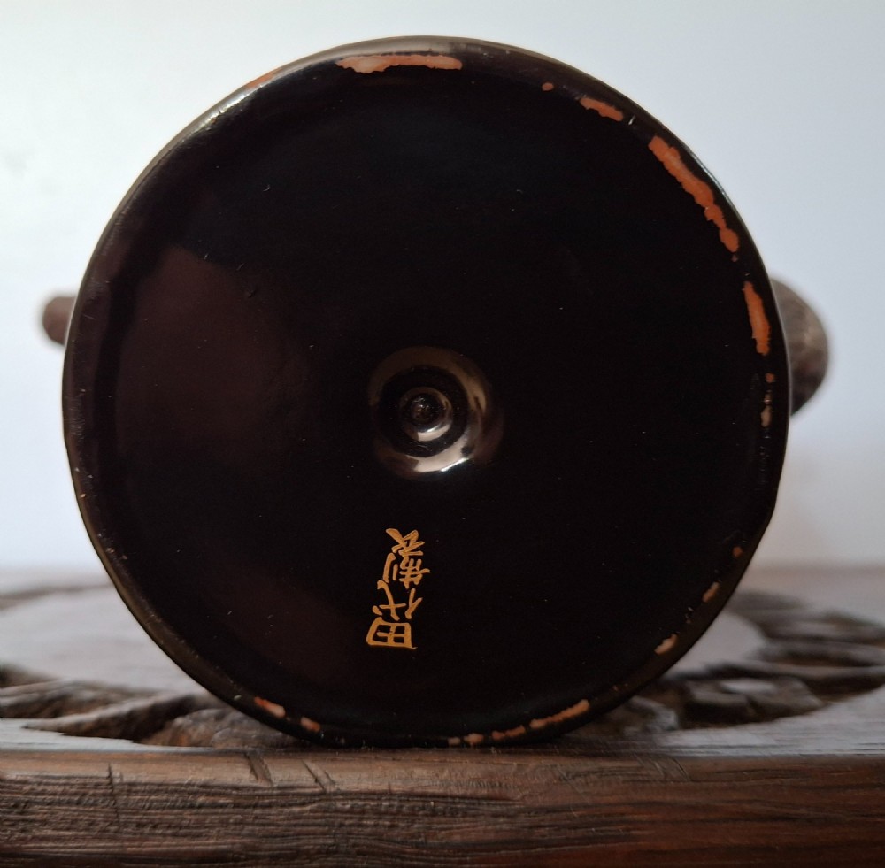 A Japanese Totai Shippo teapot with a textured tree-bark surface and green enamel dragon decoration, resting on a carved wooden base. View XII