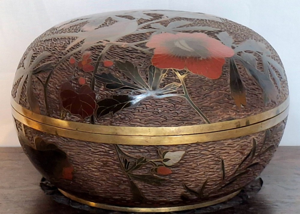 A round antique Japanese Totai Shippo covered box with a textured tree bark enamel surface decorated with red flowers, birds, and brass rim detailing.
