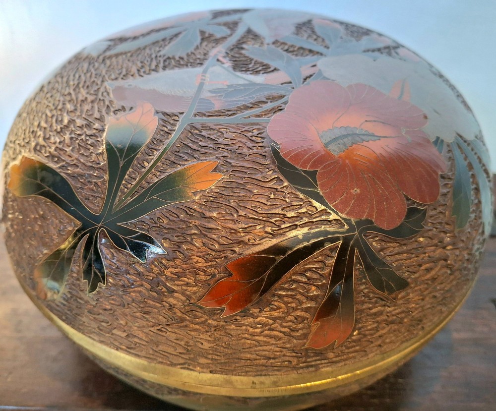 A round antique Japanese Totai Shippo covered box with a textured tree bark enamel surface decorated with red flowers, birds, and brass rim detailing. View III