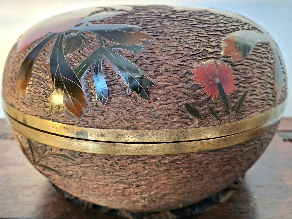 A round antique Japanese Totai Shippo covered box with a textured tree bark enamel surface decorated with red flowers, birds, and brass rim detailing. View V