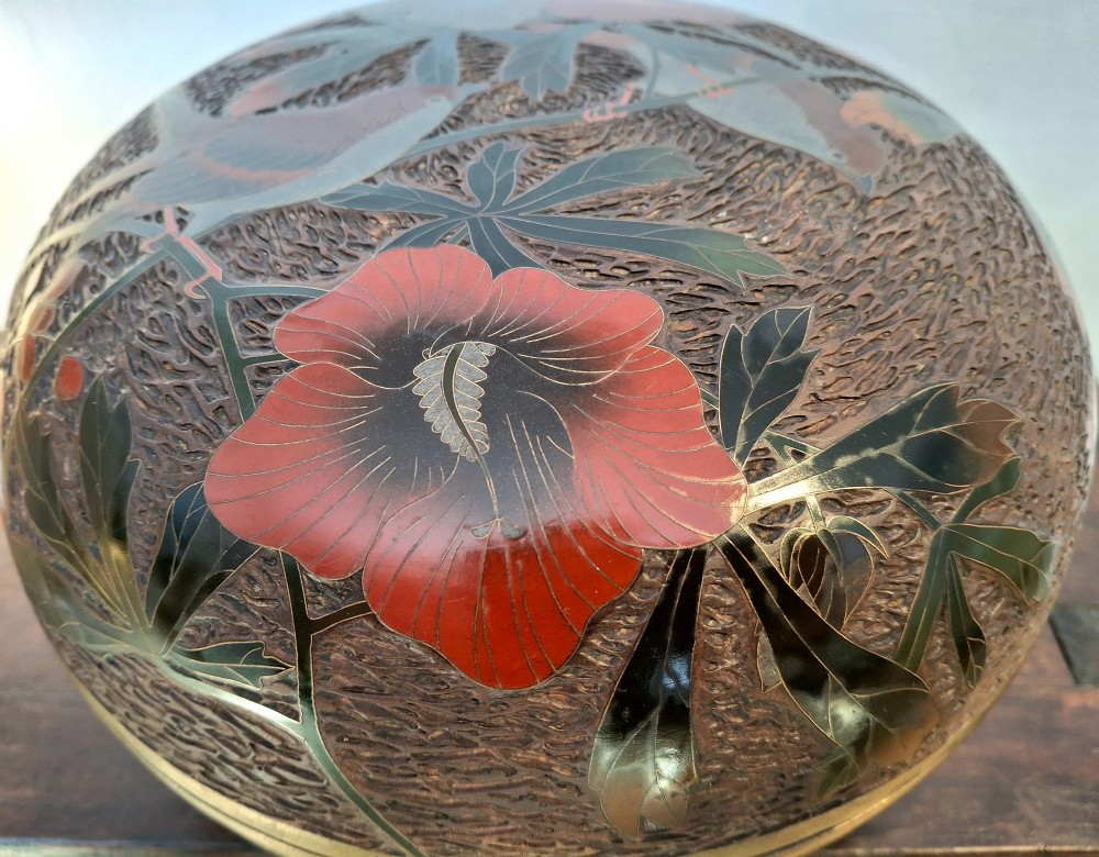 A round antique Japanese Totai Shippo covered box with a textured tree bark enamel surface decorated with red flowers, birds, and brass rim detailing. View X