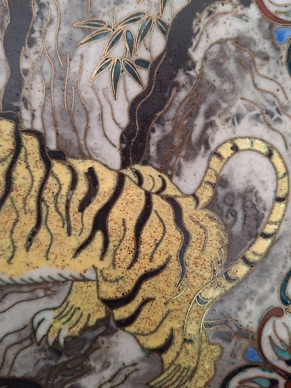 A circular Japanese cloisonne enamel dish depicting a yellow tiger beside bamboo and rocks against a turquoise blue ground with a stylized border. View IV