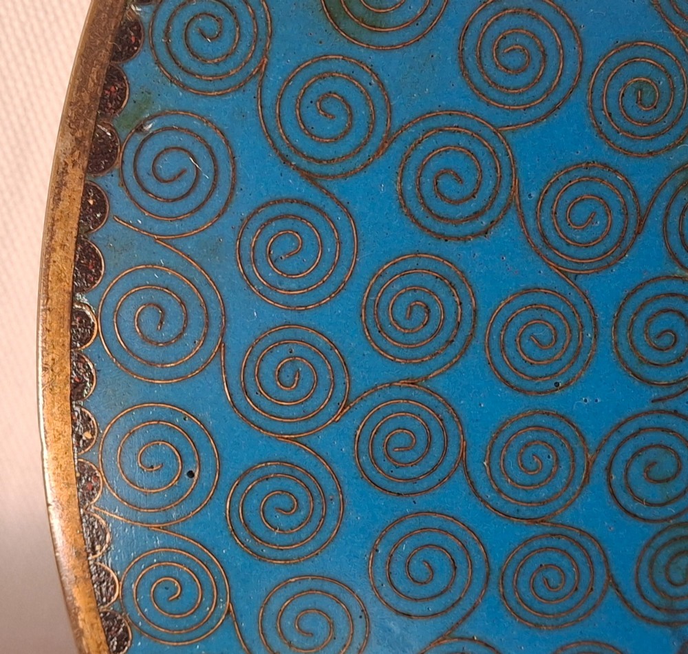 A circular Japanese cloisonne enamel dish featuring a central yellow reserve with a bird and chrysanthemums alongside lotus flowers against geometric mosaic patterns. View XI