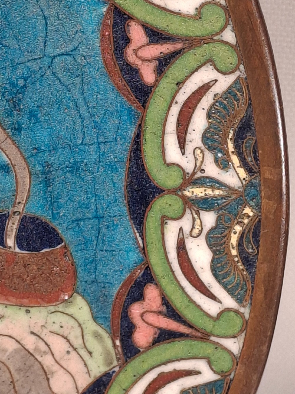 A circular Japanese cloisonne enamel plate depicting a bearded seated figure beside a smoking pot on a turquoise background with a floral border. View VIII