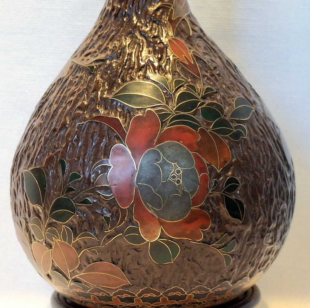 A pear-shaped Japanese Totai Shippo ceramic vase featuring textured brown tree bark enamel with cloisonne bird and floral motifs, resting on a carved dark wood stand. View X
