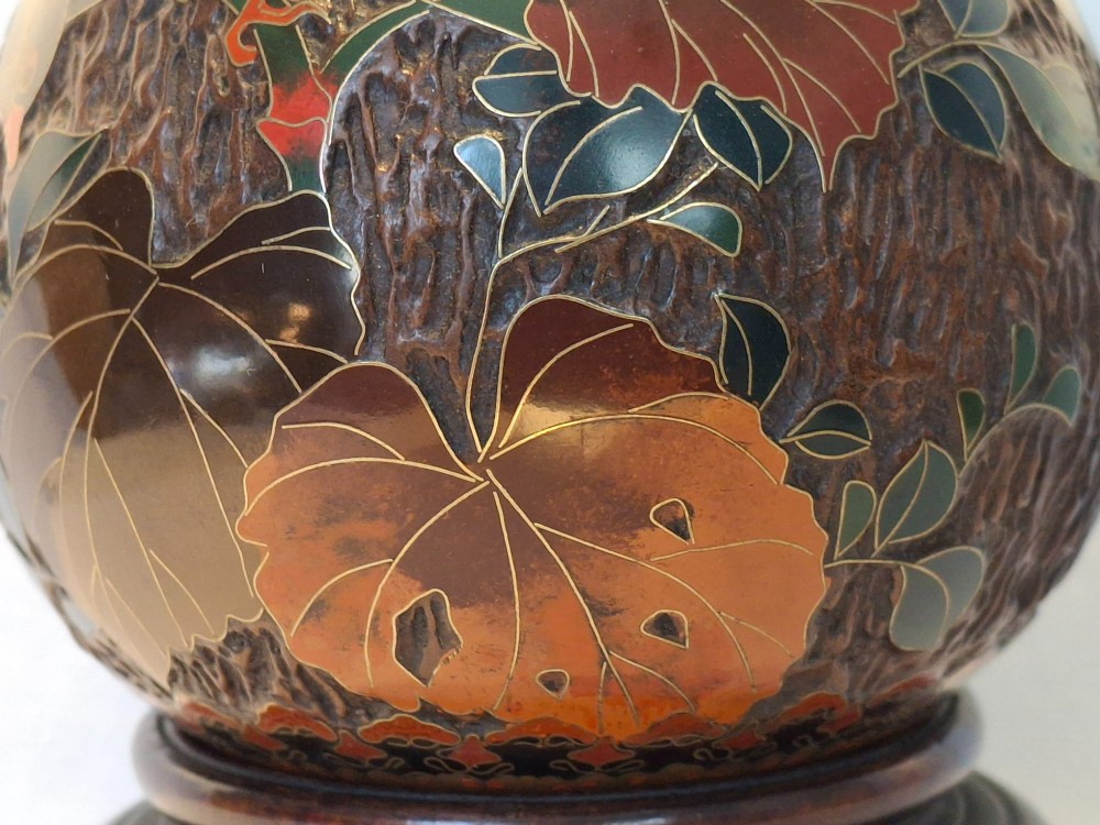 A bulbous Japanese porcelain vase featuring a dark brown tree bark texture decorated with cloisonne enamel birds and foliage on a wooden base. View XIII