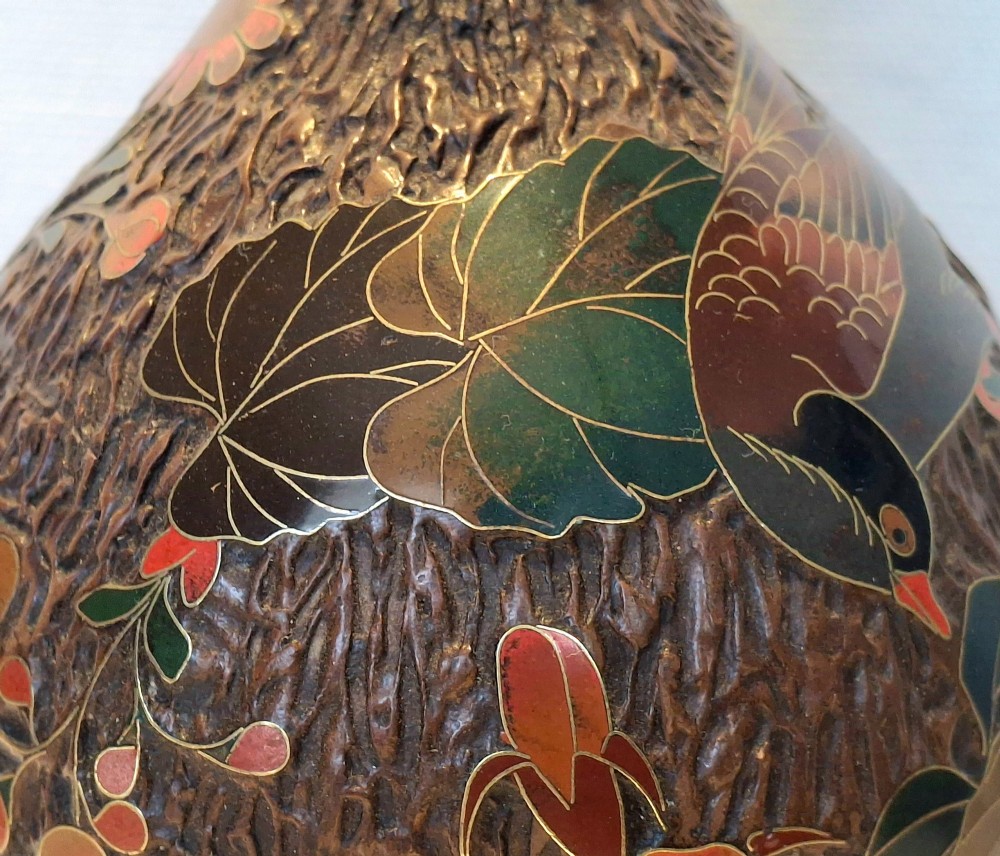 A bulbous Japanese porcelain vase featuring a dark brown tree bark texture decorated with cloisonne enamel birds and foliage on a wooden base. View XV