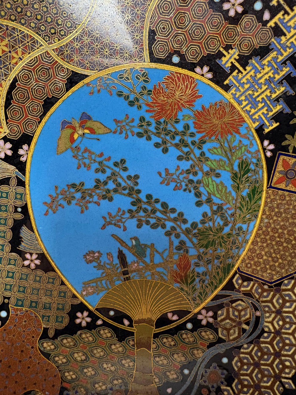 A circular Japanese Meiji period cloisonne charger featuring a sky-blue central medallion with chrysanthemums, a butterfly, and a frog, framed by geometric enamel patterns. View II