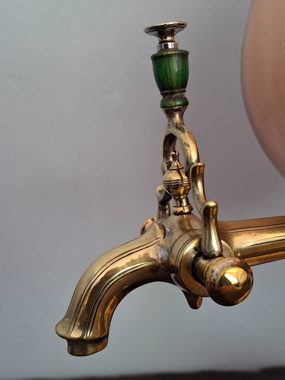 An antique polished copper and brass tea urn featuring a urn-shaped body, crest finial, side handles, and a spigot, resting on a square pedestal base. View XV