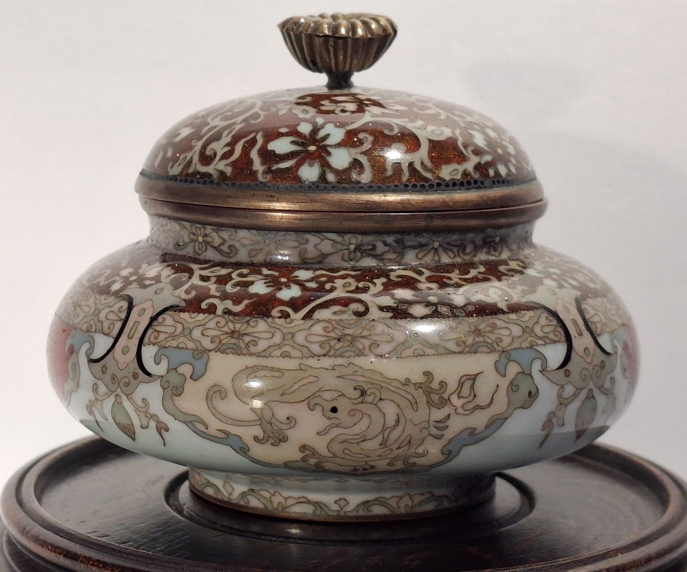 A Japanese cloisonne enamel koro decorated with phoenix motifs and intricate floral scrollwork, topped with a domed lid and carved finial. View II