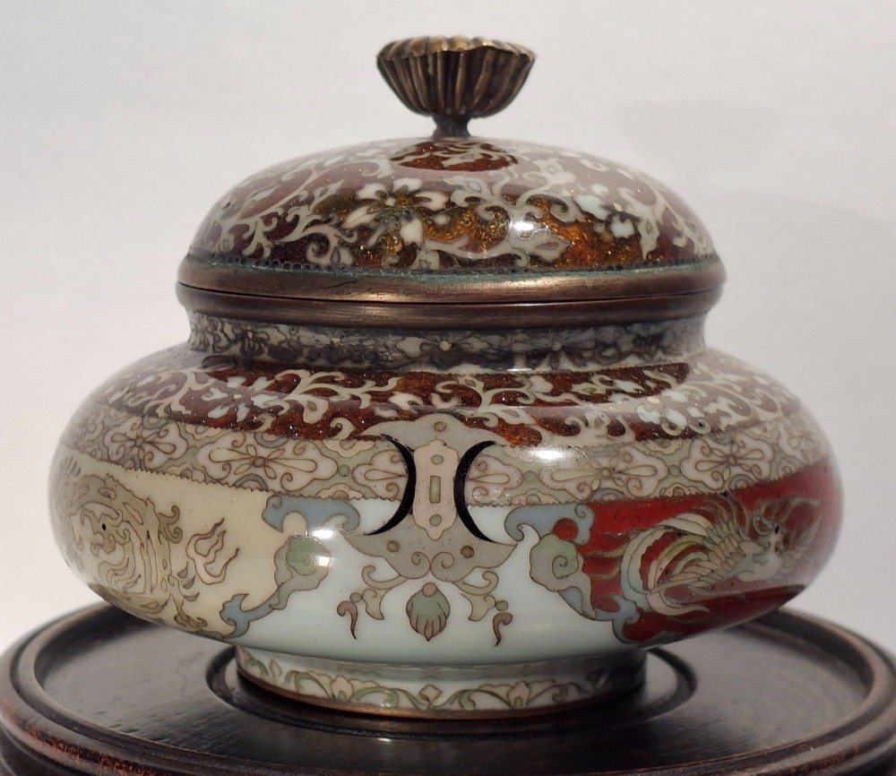 A Japanese cloisonne enamel koro decorated with phoenix motifs and intricate floral scrollwork, topped with a domed lid and carved finial. View V