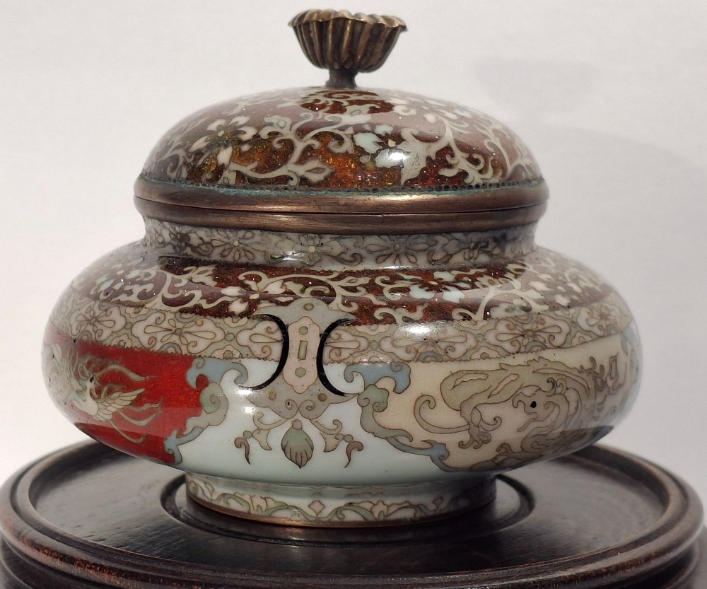 A Japanese cloisonne enamel koro decorated with phoenix motifs and intricate floral scrollwork, topped with a domed lid and carved finial. View VI