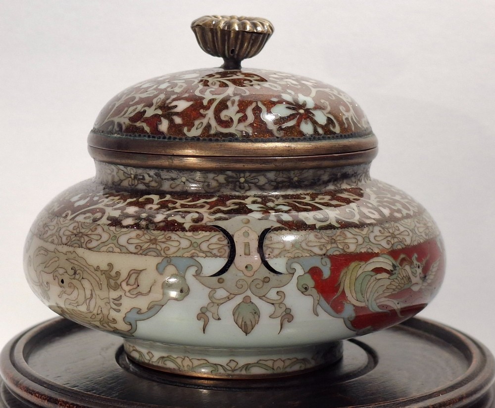 A Japanese cloisonne enamel koro decorated with phoenix motifs and intricate floral scrollwork, topped with a domed lid and carved finial. View VII