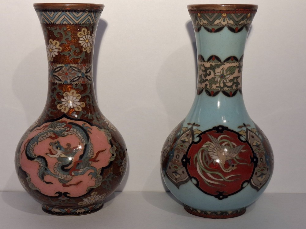 A pair of Japanese Meiji period cloisonne enamel miniature vases featuring detailed dragon and phoenix medallions on brown and light blue grounds.