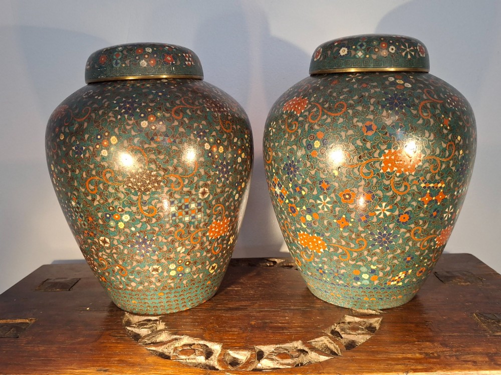 A pair of rounded Japanese cloisonne enamel ginger jars decorated with dense green foliage scrollwork and colourful floral motifs with domed lids. View II