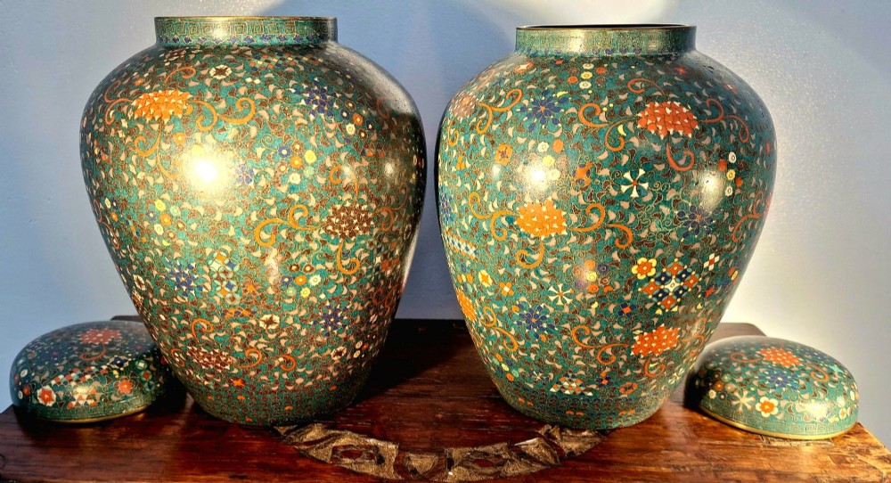 A pair of rounded Japanese cloisonne enamel ginger jars decorated with dense green foliage scrollwork and colourful floral motifs with domed lids. View IX