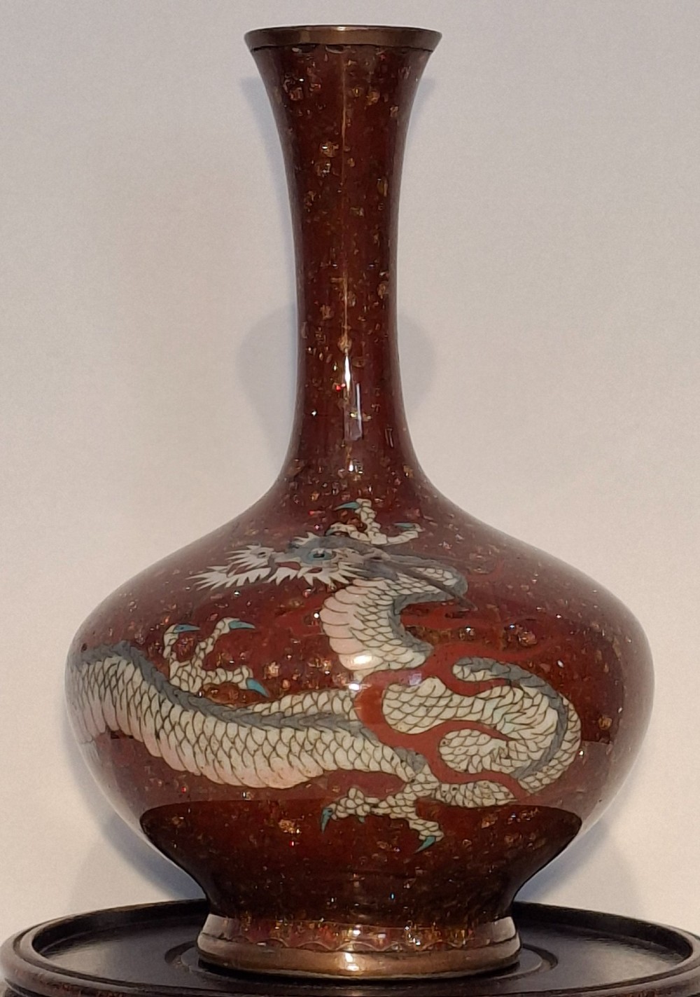 A miniature dark red Japanese cloisonne enamel vase featuring a detailed coiled dragon motif and a slender neck.
