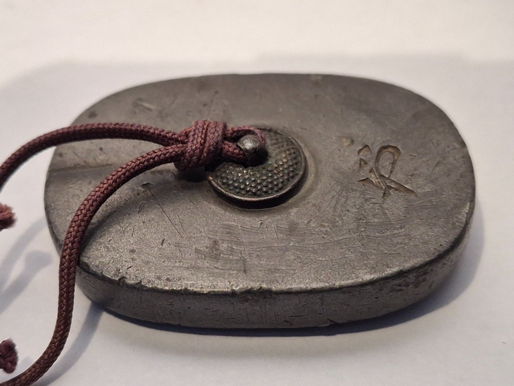 An oval-shaped pewter Japanese manju netsuke featuring champleve enamel floral decoration and an attached cord. View III