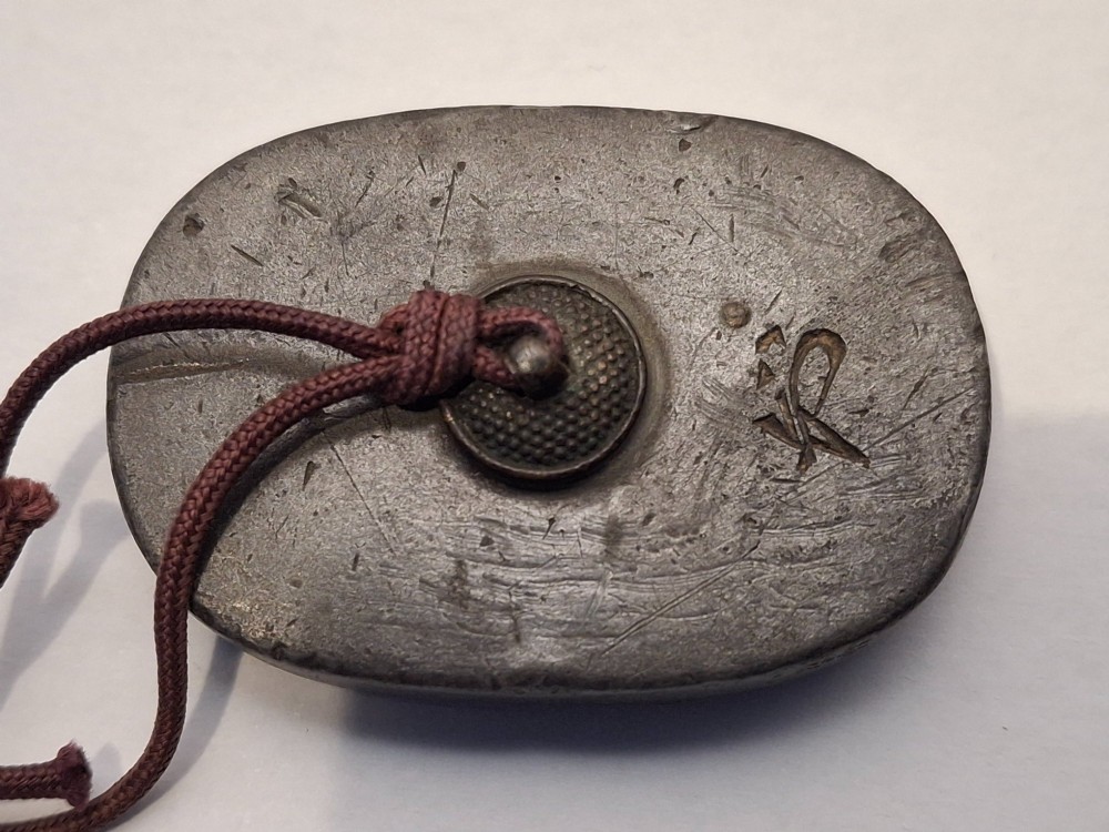 An oval-shaped pewter Japanese manju netsuke featuring champleve enamel floral decoration and an attached cord. View IV