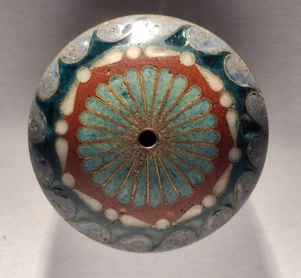 A circular Japanese manju netsuke in polychrome cloisonne enamel with central floral medallion and spiral border patterns. View VII