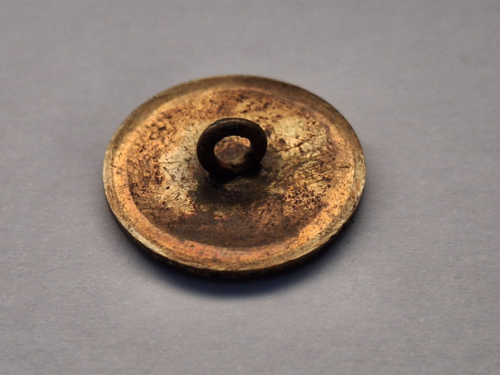A circular Japanese manju netsuke in polychrome cloisonne enamel with central floral medallion and spiral border patterns. View XIII