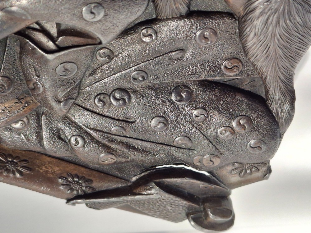 A dark bronze Japanese Takazogan metal tray depicting a figure in patterned robes reacting to a monkey perched on his shoulder. View VII