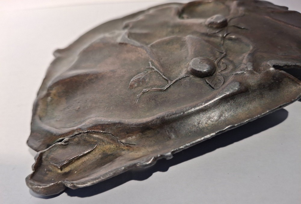 A dark bronze Japanese Takazogan metal tray depicting a figure in patterned robes reacting to a monkey perched on his shoulder. View X
