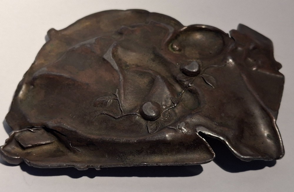 A dark bronze Japanese Takazogan metal tray depicting a figure in patterned robes reacting to a monkey perched on his shoulder. View XI