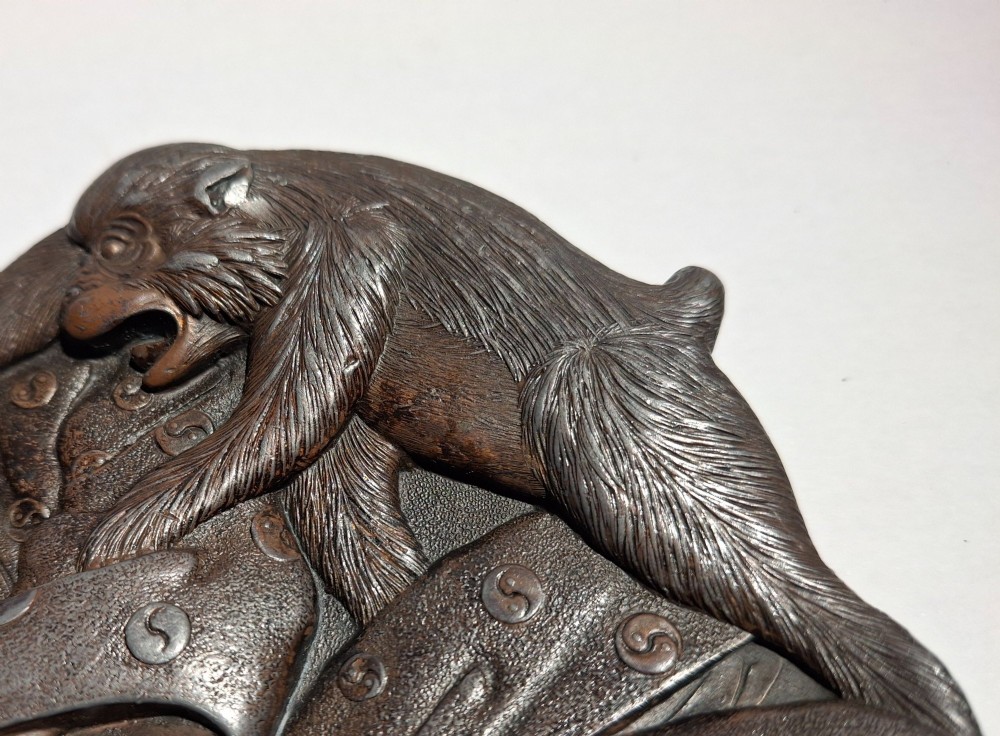 A dark bronze Japanese Takazogan metal tray depicting a figure in patterned robes reacting to a monkey perched on his shoulder. View XV