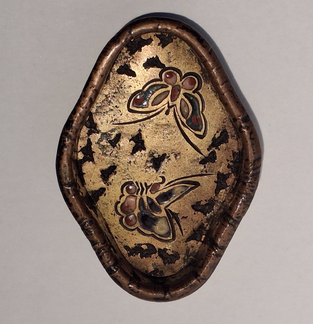 An oval-shaped antique Japanese bronze recessed door pull featuring two decorative enamel butterflies against a textured gilded background.