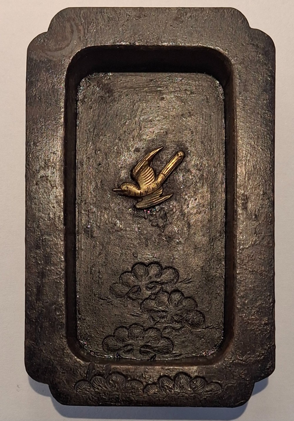 A rectangular dark bronze recessed Japanese hikite door pull decorated with a gilt bird in flight and carved pine tree motifs.