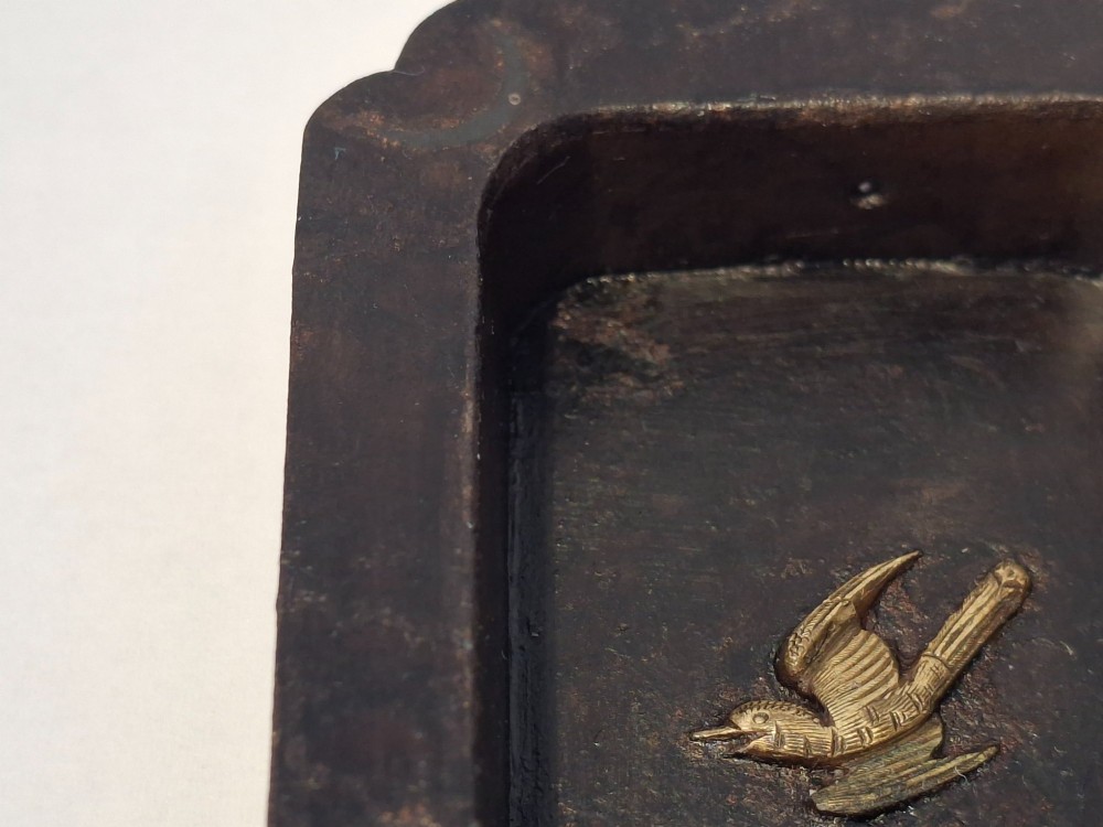 A rectangular dark bronze recessed Japanese hikite door pull decorated with a gilt bird in flight and carved pine tree motifs. View VIII