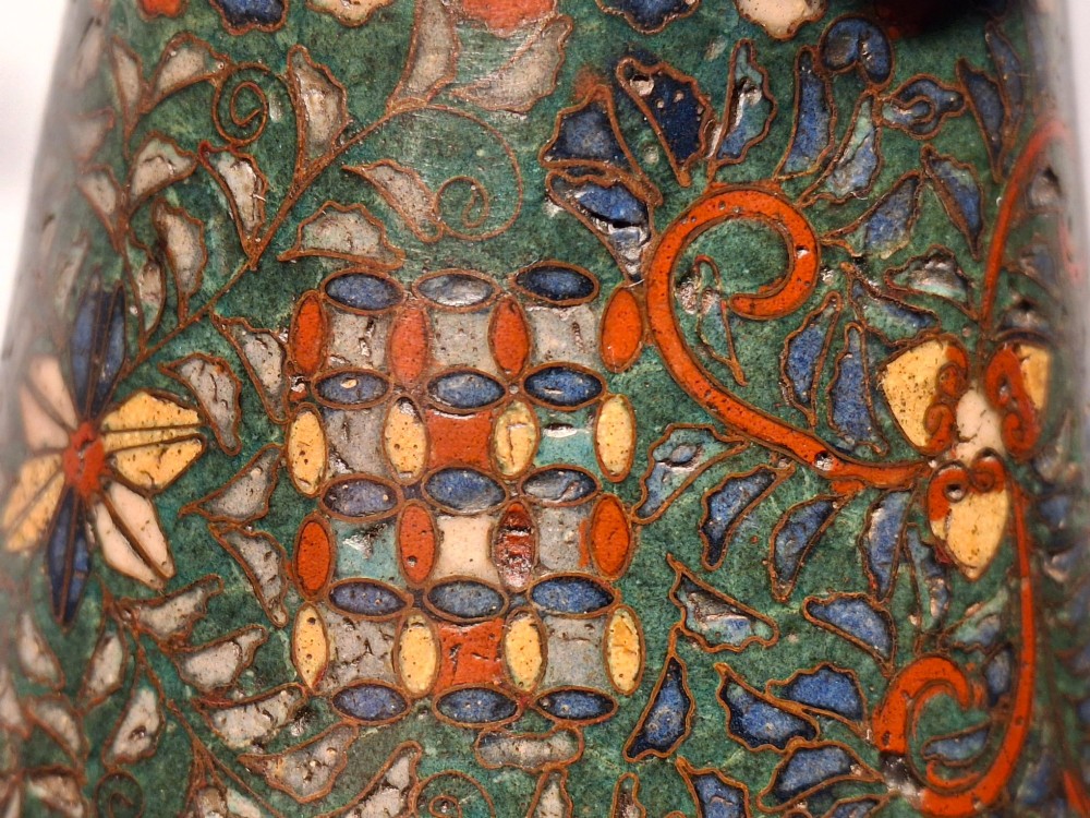 A miniature Japanese cloisonne enamel ritual vase with two loop handles, loose rings, and polychrome floral decoration on a dark green background. View XIII