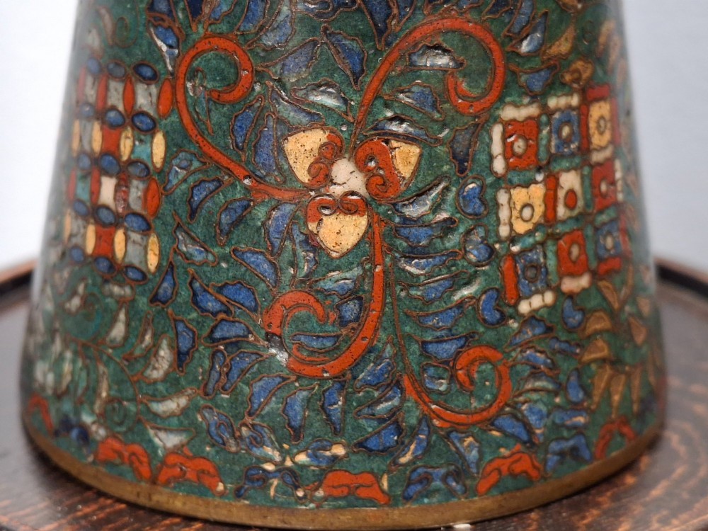 A miniature Japanese cloisonne enamel ritual vase with two loop handles, loose rings, and polychrome floral decoration on a dark green background. View XIV