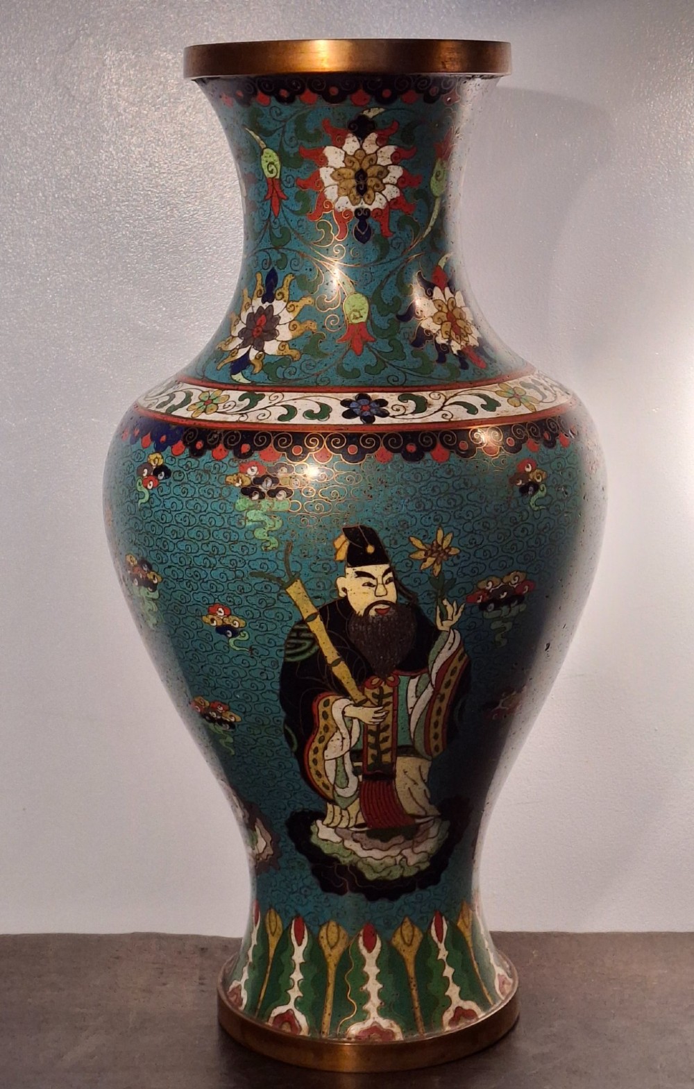 A large Chinese cloisonne enamel baluster vase decorated with scholar figures on a turquoise scrollwork ground with gilded rims.