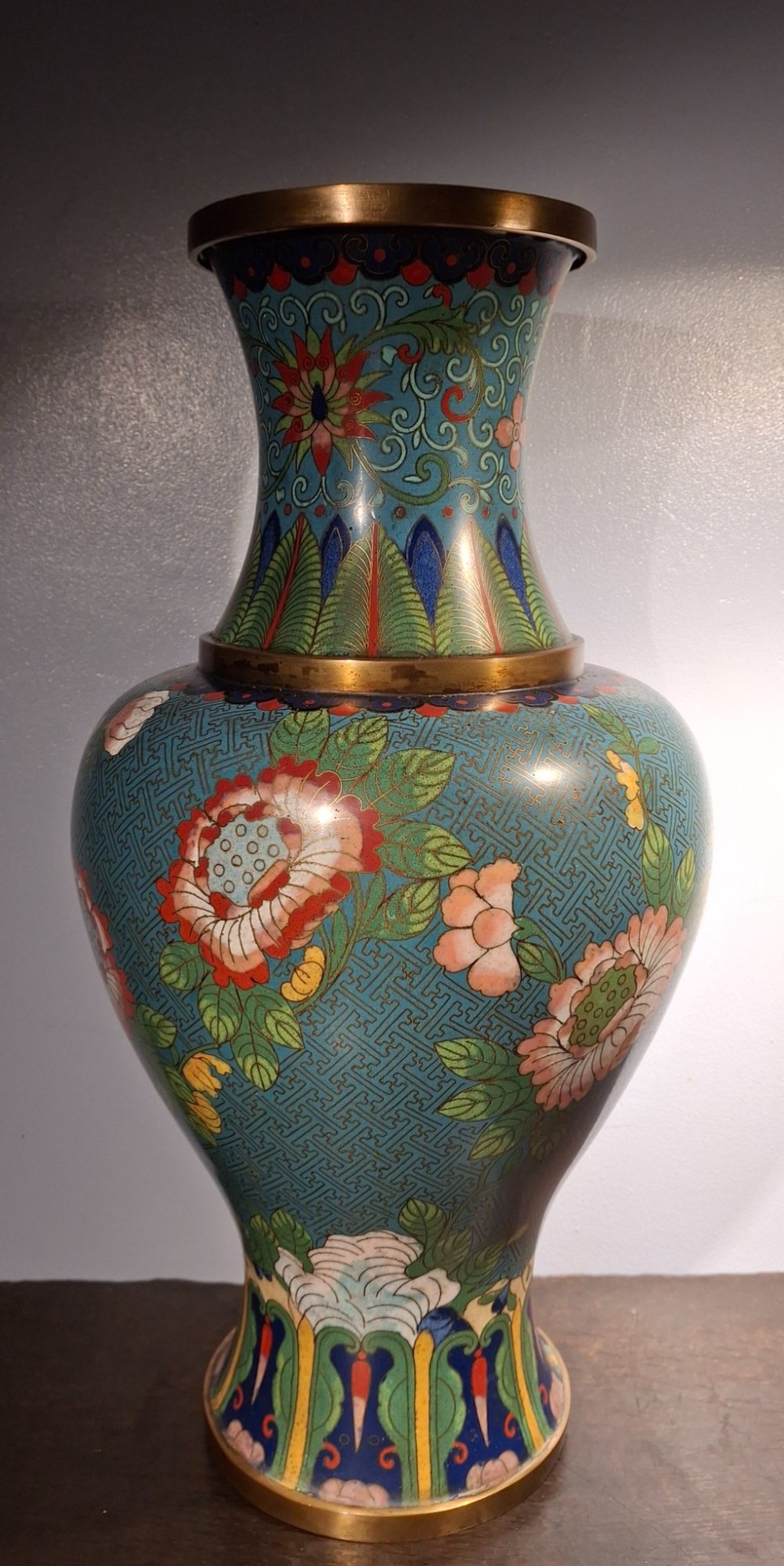 A large Chinese cloisonne enamel vase with pink and yellow floral motifs over a blue geometric ground and brass rim. View IV