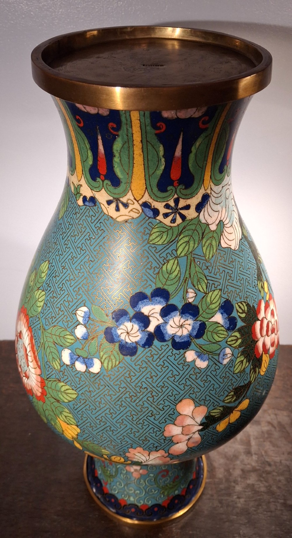 A large Chinese cloisonne enamel vase with pink and yellow floral motifs over a blue geometric ground and brass rim. View XIV