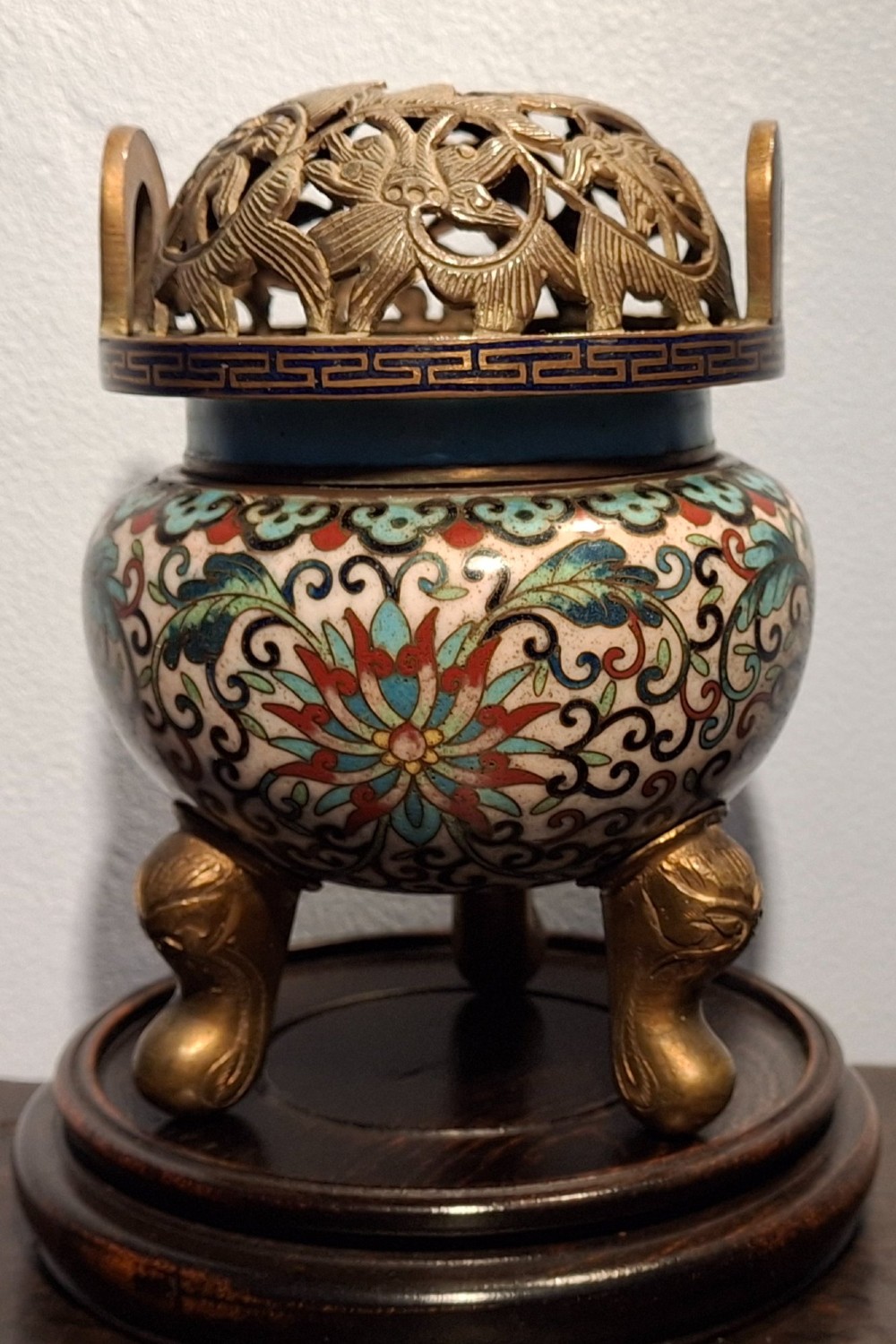 A 19th-century Chinese tripod cloisonne enamel censer featuring intricate floral scrollwork, upright loop handles, three gilded cabriole feet, and a pierced brass cover. View III