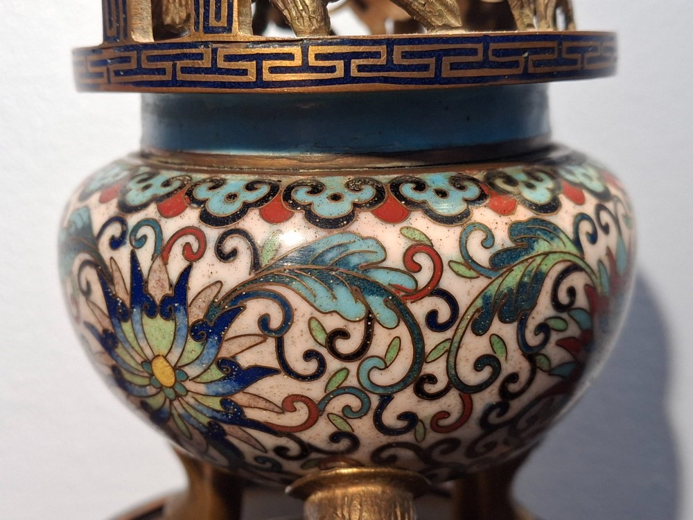 A 19th-century Chinese tripod cloisonne enamel censer featuring intricate floral scrollwork, upright loop handles, three gilded cabriole feet, and a pierced brass cover. View VI
